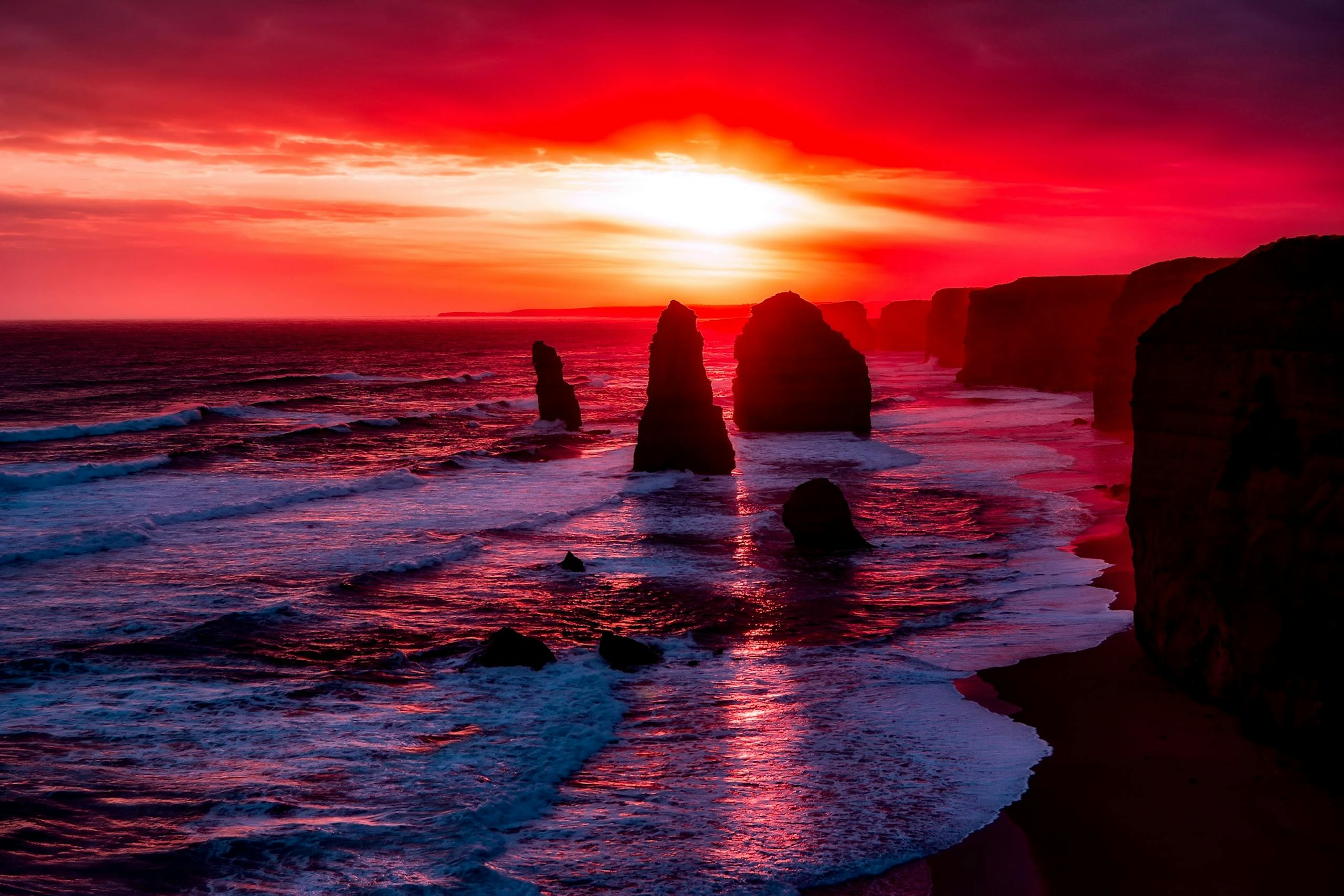 Dramatic sunset at Twelve Apostles showcasing vibrant sky and ocean reflections.